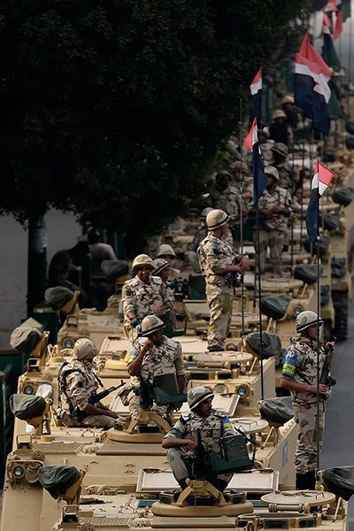 مجموعة من الطلاب يقدمون فقرات الإذاعة المدرسية بحماس في ساحة المدرسة أمام زملائهم